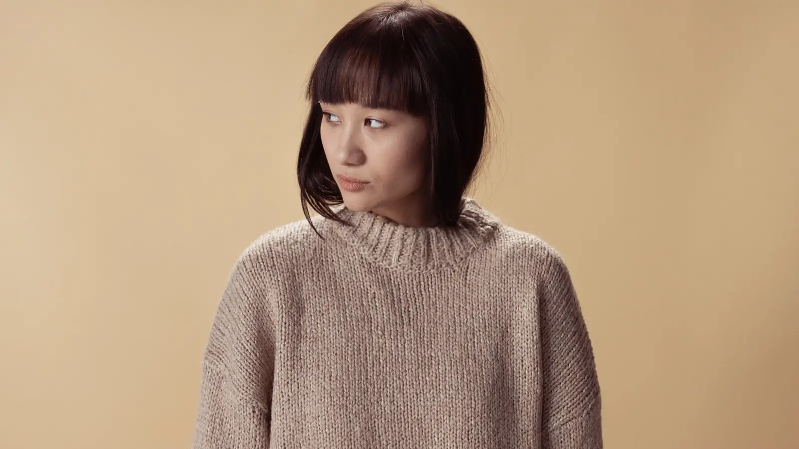 A model wearing a neutral wool knit sweater